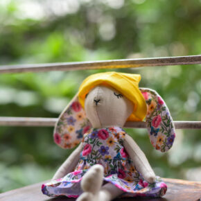 Handmade fabric bunny doll in floral dress and yellow hat