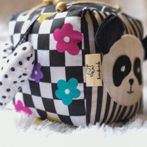 Black and white activity cube with panda face, squeaky heart, bead slider, teether ring, button activity and ribbon taggies